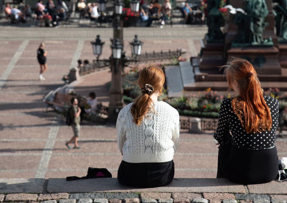 Two women in Finland watch busy town square.