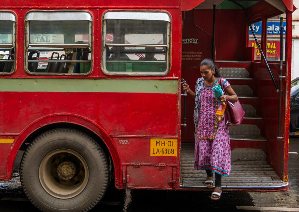 Woman stepping off of a double decker bus in India.