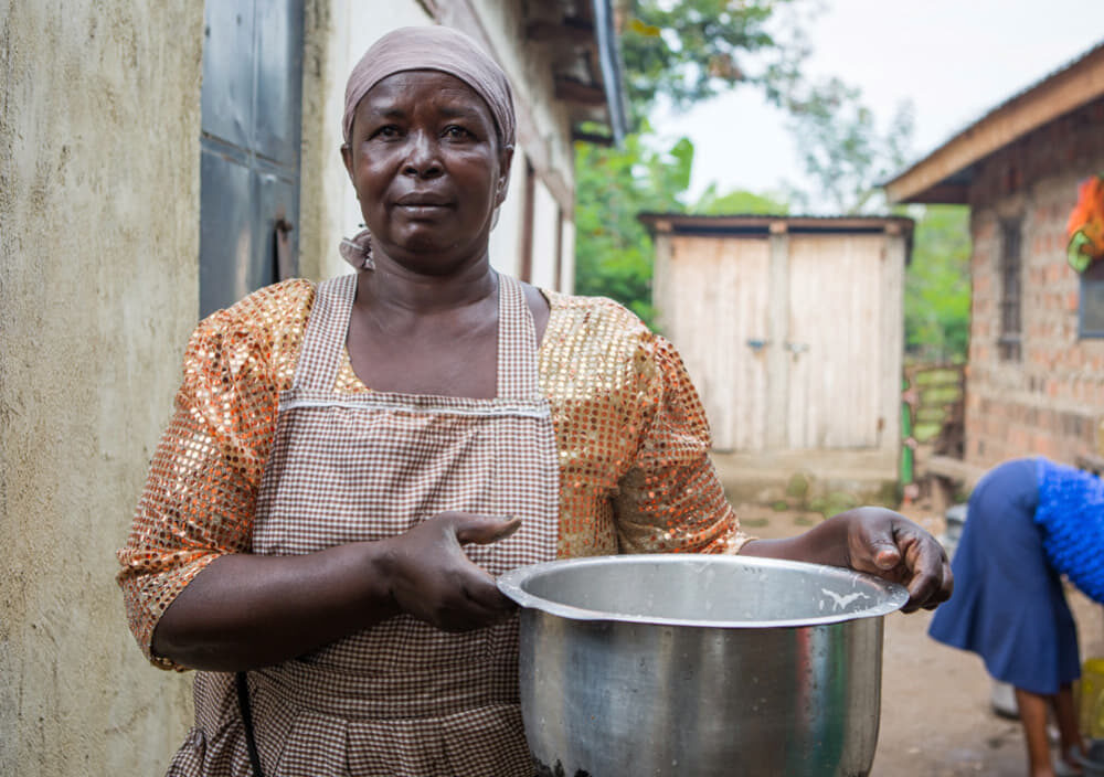 Kenyan woman carrying a large cooking cauldron.